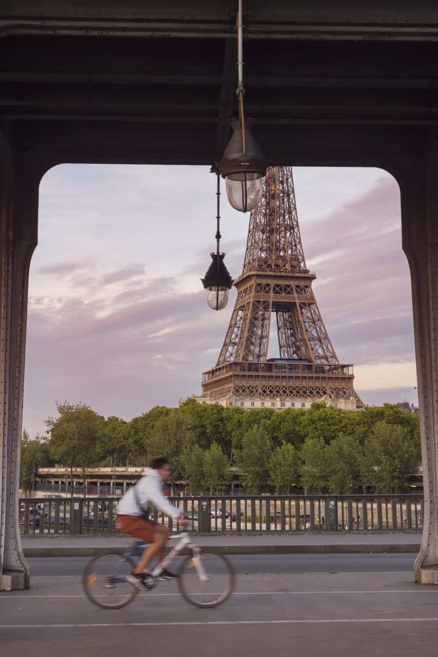 Pont de Bir Hakeim Another one of my favourite locations is this bridge which is perfectly located right near the Eiffel Tower across the River Seine. From Pont de Bir Hakeim you get a direct view towards the Eiffel Tower and there’s usually some gorgeous houseboats moored along the river to add something extra to your shot. The bridge itself has some shiny black railings that are great to use for creating your own reflections by spilling some water and making little puddles! The bridge has a central section with ornate arches that repeat their way along under the railway. This is a great subject to use for framing the Eiffel Tower and also capturing people passing by on their bicycles. Photo Tip: Take a water bottle to create puddles along the railings, the surface is perfect for creating reflections so you don’t even need to wait for a rainy day! When to visit: This is one of those spots that’s rarely popular at sunset so it’s a great time to venture away from the crowds of Trocadero and find yourself a great perspective to watch the sky change colours above the Eiffel Tower.