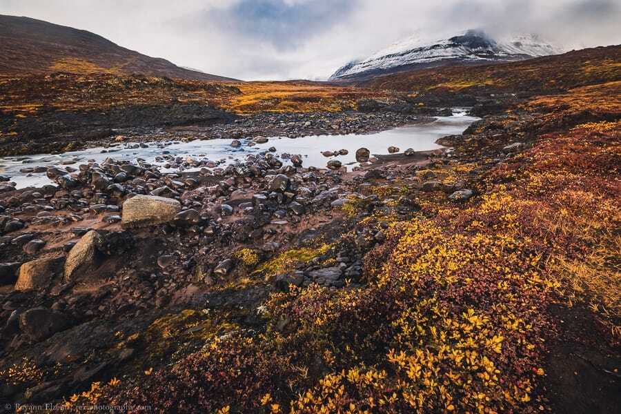 River, autumn colours and snow-covered peak on Disko Island
